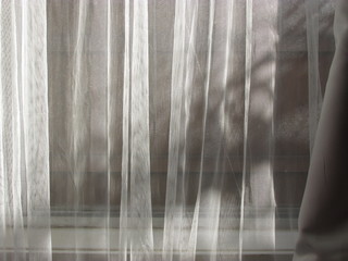 Low angle sunlight shining through a pair of sheer curtains
