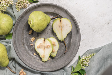 Tasty pears with nuts. A table decorated with flowers and a plate of pears cut into the plate