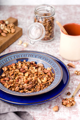honey granola with nuts, in two blue plate, for breakfast, glass jar, on table, vertical