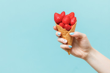 Woman holding waffle cones on color background.