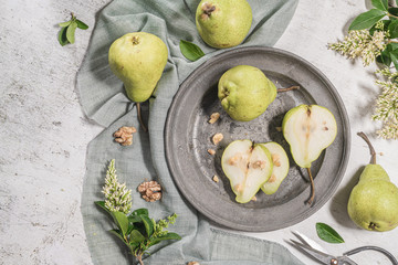 Tasty pears with nuts. A table decorated with flowers and a plate of pears cut into the plate