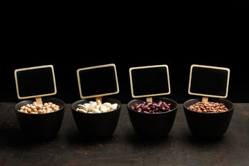 Legumbres secas en cuencos negro sobre un fondo de metal y fondo negro con cartelas y pizarras....