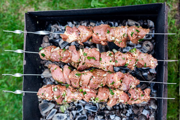 The process of cooking raw meat on skewers