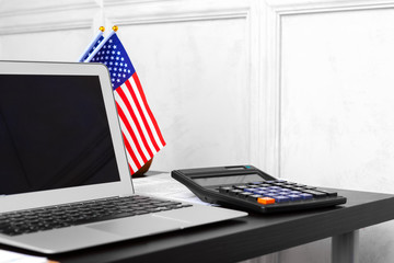 US flag and laptop on office desk top view
