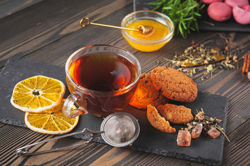 Cup of tea with lemon and honey on wooden background.