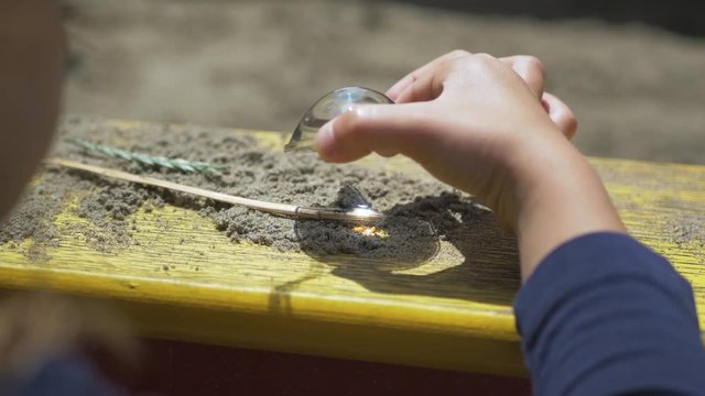Children burning the wooden by the magnifying glass in sunlight, sunbeam or sunshine