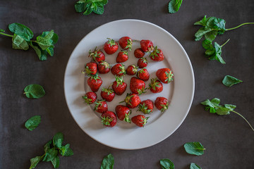 White strawberries dish on dark grey background decorated with sprigs of mint