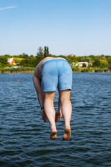 Young man jumping into lake