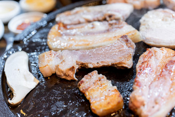 Pan-fried cooked black pork meal in Korea restaurant, fresh delicious korean food cuisine on iron plate with lettuce, close up, copy space, lifestyle