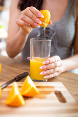 cooking, food and concept of veganism, vigor and healthy eating - close up of female hand squeeze fresh orange juice
