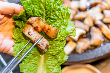 Pan-fried cooked black pork meal in Korea restaurant, fresh delicious korean food cuisine on iron plate with lettuce, close up, copy space, lifestyle