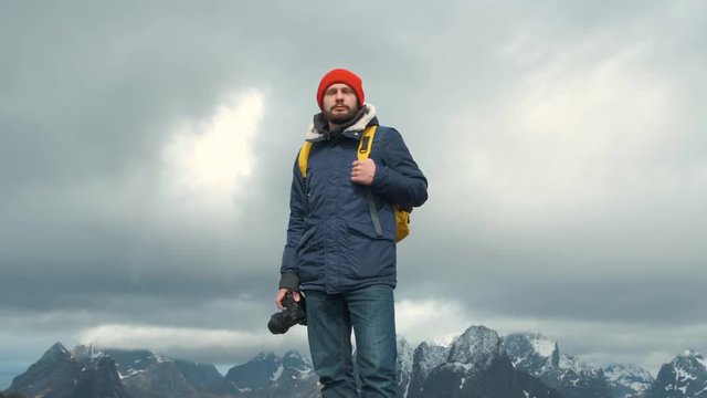 Portrait photographer on top a mountain. Professional photographer male taking photograph of valley with DSLR wearing backpack photographing scenic landscape nature travel adventure Norway