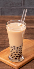 Delicious bubble milk tea with straw in drinking glass on wooden table background, concept of reduce plastic to go in Taiwan, close up, copy space