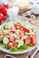 Caesar salad with salted salmon on a white plate, selective focus