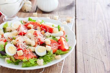 Caesar salad with salted salmon on a white plate, horizontal, copy space