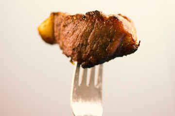 Fried meat on a light background. Barbecue on the fork