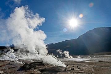 Bright rising sun above erupting Hot Geyser Of Steam in El Tatio Geysers field at early morning sunrise, Atacama desert, Chile