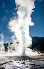Atacama desert, Chile: Bright rising sun behind erupting Hot Geyser Of Steam in El Tatio Geysers field at early morning sunrise
