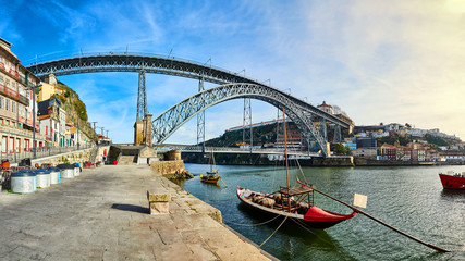 Traditional boats with wine barrels on Douro river in old Porto with background of Dom Luis bridge, Portugal