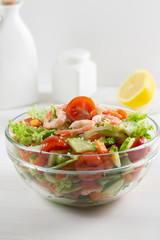 Salad from fresh vegetables and seafood tomatoes cucumber greens sesame shrimp in a transparent glass bowl. Vegan vegetarian food, fresh sliced vegetables vitamins diet