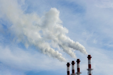 The red-white pipes of the boiler room release white steam into the blue sky. Pipes boiler for heating of multi-storey residential buildings