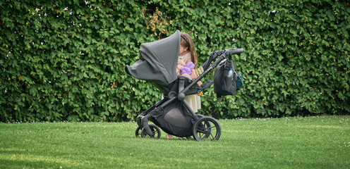 Soft stroller baby stroller with an unidentified girl next to the stroller caring for the baby