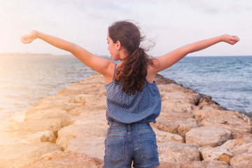 TEENAGER WITH HANDS UP ON THE BEACH
