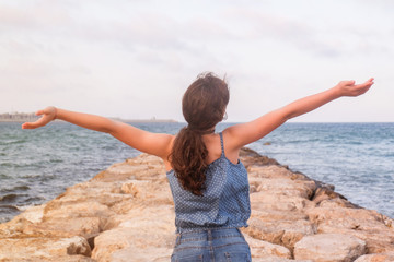 TEENAGER WITH HANDS UP ON THE BEACH