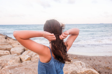 teenager picking her hair in a ponytail on the beach