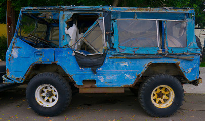 dilapidated rusty blue truck on the middle of the street