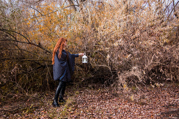 young redhead woman with white lamp in the hand in autumn park