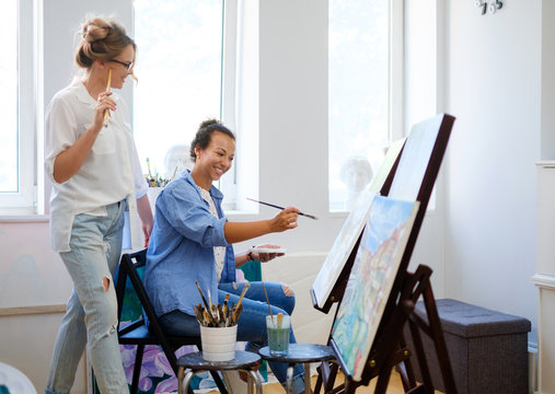 Creative Painter And Her Protege Working In A Studio