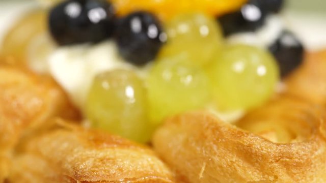 Close up puff pastry pie decorated with fresh blueberry and fruit slices - kiwi, grapes, ananas