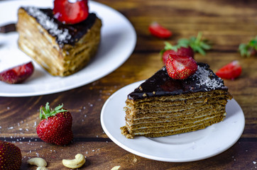 Honey cake with chocolate glaze and buttercream. Served with strawberry and nuts. Birthday sweet dessert