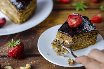 Honey cake with chocolate glaze and buttercream. Served with strawberry and nuts. Birthday sweet dessert