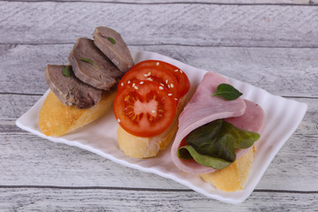 Bruschetta with tomato, ham and tongue
