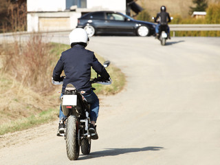 Fototapeta premium Motorcyclist rides on the highway on a moped with a backpack. Sound shields guard against traffic noise. Travel by motorcycle. Symbol of freedom and aspiration forward. Left side traffic