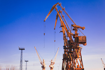 Mobile harbor cranes over blue sky. Transport and technology concept