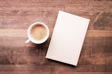 Cup of hot coffee with notebook on wooden table background, top view