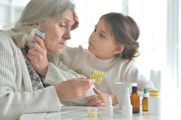 Obraz na płótnie Canvas Cute girl giving medicine to sick senior woman