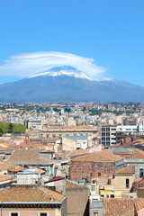 Fototapeta na wymiar Vertical picture capturing famous Mount Etna overlooking the Sicilian city Catania, Italy. Smoke cloud over the famous volcano, snow on the top. The beautiful city is a popular tourist destination