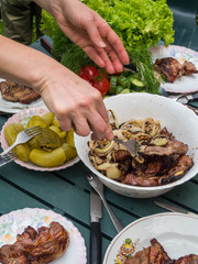 women hand bbq, eating healthy fresh salad and barbecue meat at outdoor barbecue garden party gathering, selective focus