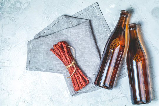 Craft beer with sausages kabanosi on gray surface