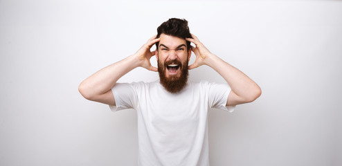Photo of a frustrated bearded man, having headache and screaming