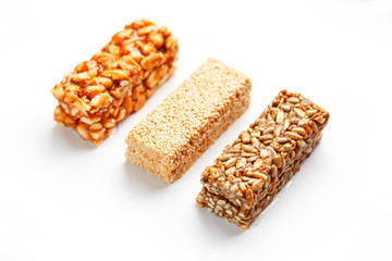 Grain granola bar with peanuts, sesame and seeds in a row on a white background. Top view Three assorted bars, isolate