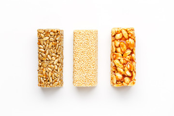 Grain granola bar with peanuts, sesame and seeds in a row on a white background. Top view Three assorted bars, isolate