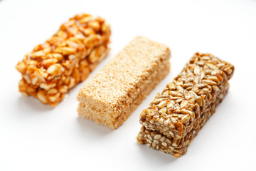 Grain granola bar with peanuts, sesame and seeds in a row on a white background. Top view Three assorted bars, isolate