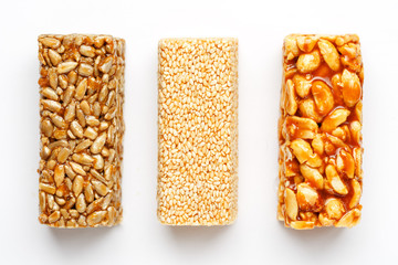 Grain granola bar with peanuts, sesame and seeds in a row on a white background. Top view Three...
