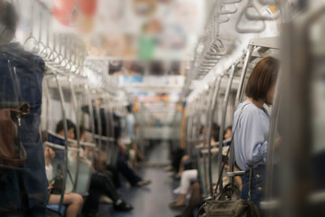 In the morning, many people, both men and women are standing and sitting on the subway who are...