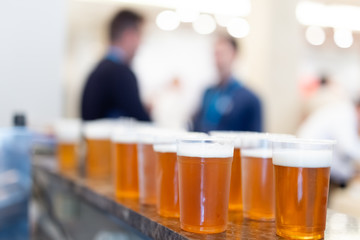 Bar counter full of beer in plastic glasses.